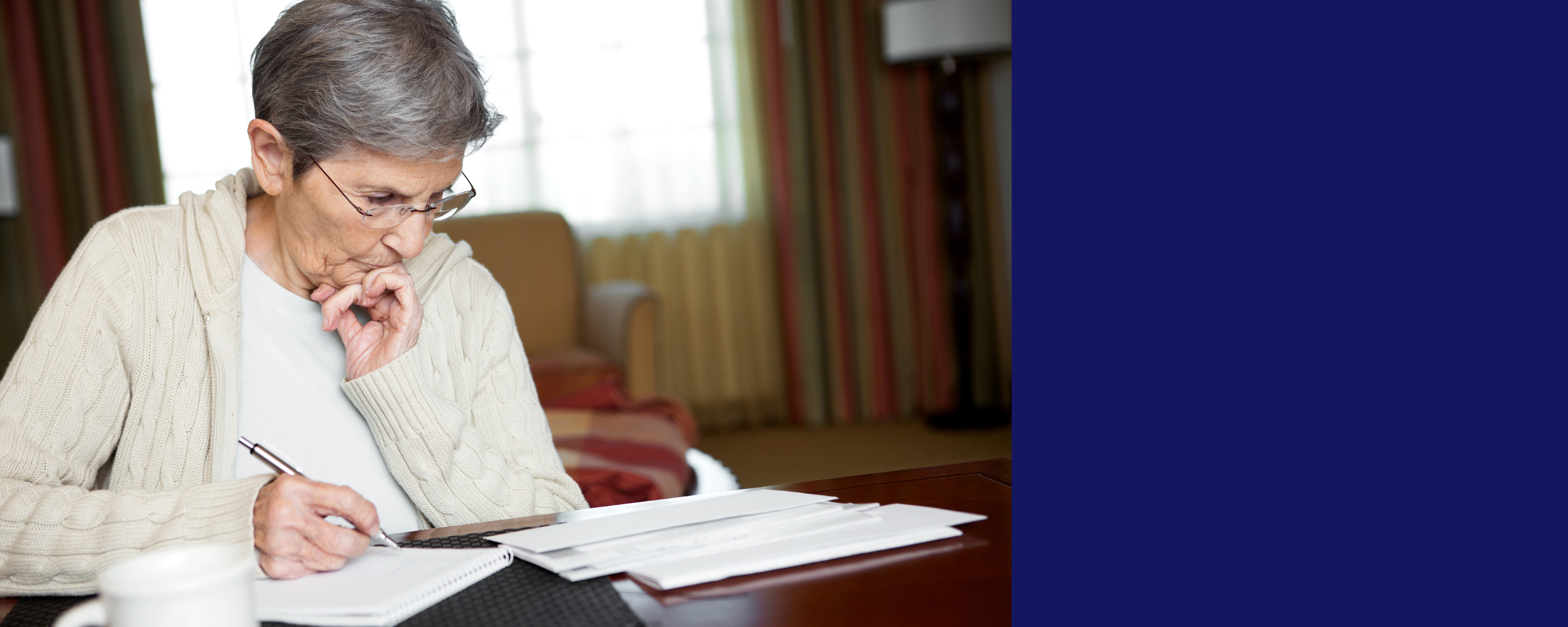 older woman sitting at a table looking at paperwork